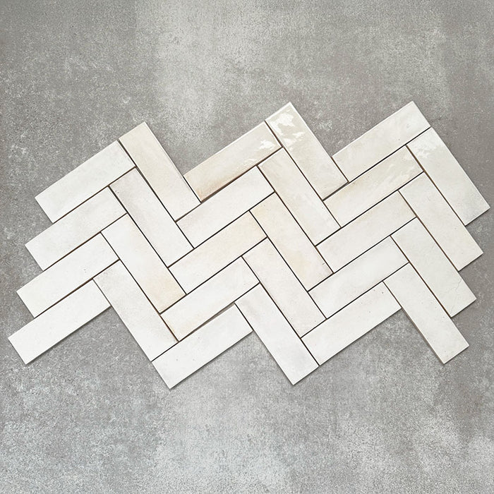Saigon White Brick Wall tiles laid in a herringbone pattern, showcasing Moroccan-style 5.1 × 16.1cm glossy ceramic tiles in soft white tones with subtle tonal variation.