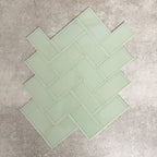 Pimlico Lime Green 7.5 × 15cm ceramic tiles with a crackle glaze finish, shown in a herringbone layout highlighting soft green tones, subtle texture and versatile design options for bathroom or kitchen walls.