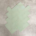 Pimlico Lime Green 7.5 × 15cm ceramic tiles with a crackle glaze finish, shown in a herringbone layout highlighting soft green tones, subtle texture and versatile design options for bathroom or kitchen walls.
