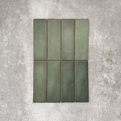 Flat lay of Zellige Malachite Green 6.5×20cm Moroccan-style ceramic brick tiles, showcasing subtle tonal variation, handmade-look texture and rich green glaze on a neutral background.