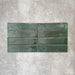 Allegra Green Gloss Brick ceramic tiles in a 6 × 25cm format, laid horizontally to highlight the deep green colour, glossy finish and subtle tonal and surface variation.
