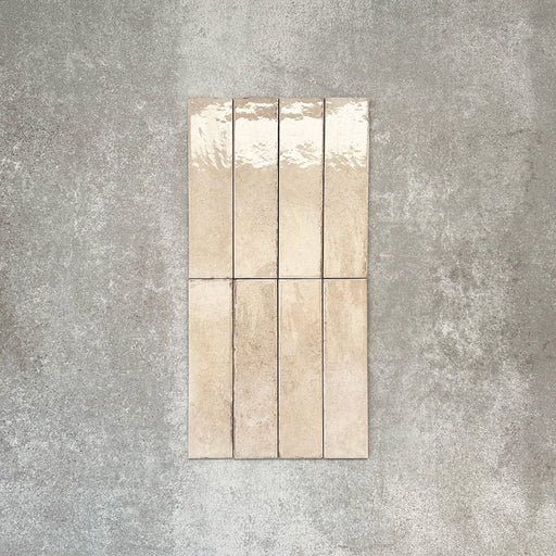 Nomad Oatmeal brick wall tiles in a 6 × 24.6cm format, shown laid together to highlight the warm neutral tone, gloss finish and subtle surface variation.