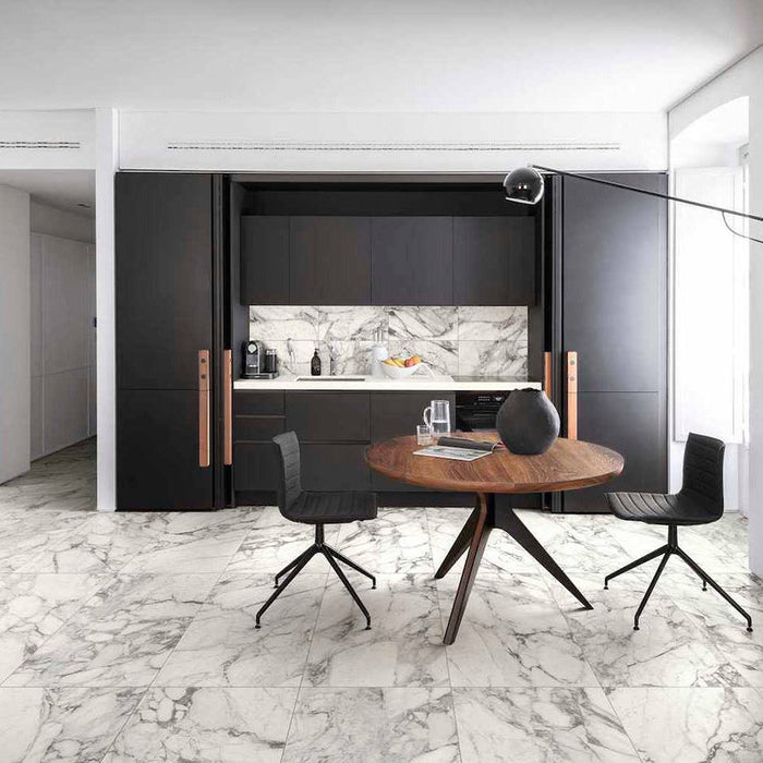 Modern kitchen and dining space featuring Hudson Calacatta Matt Marble 30 × 60cm porcelain floor tiles, showcasing a crisp white base with soft grey veining, paired with dark cabinetry, warm wood tones, and minimalist styling for a clean, contemporary finish.