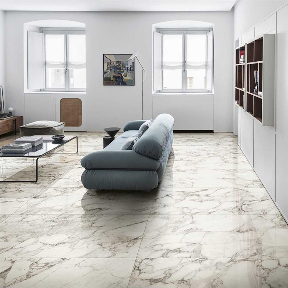 Living room featuring Hudson Calacatta Matt Marble 30 × 60cm porcelain floor tiles, showcasing a soft white base with flowing grey veining, paired with minimalist furnishings, light walls, and natural light to create a calm, open, contemporary space.