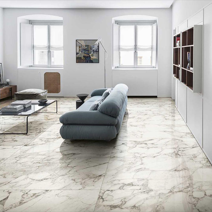 Living room featuring Hudson Calacatta Matt Marble 30 × 60cm porcelain floor tiles, showcasing a soft white base with flowing grey veining, paired with minimalist furnishings, light walls, and natural light to create a calm, open, contemporary space.