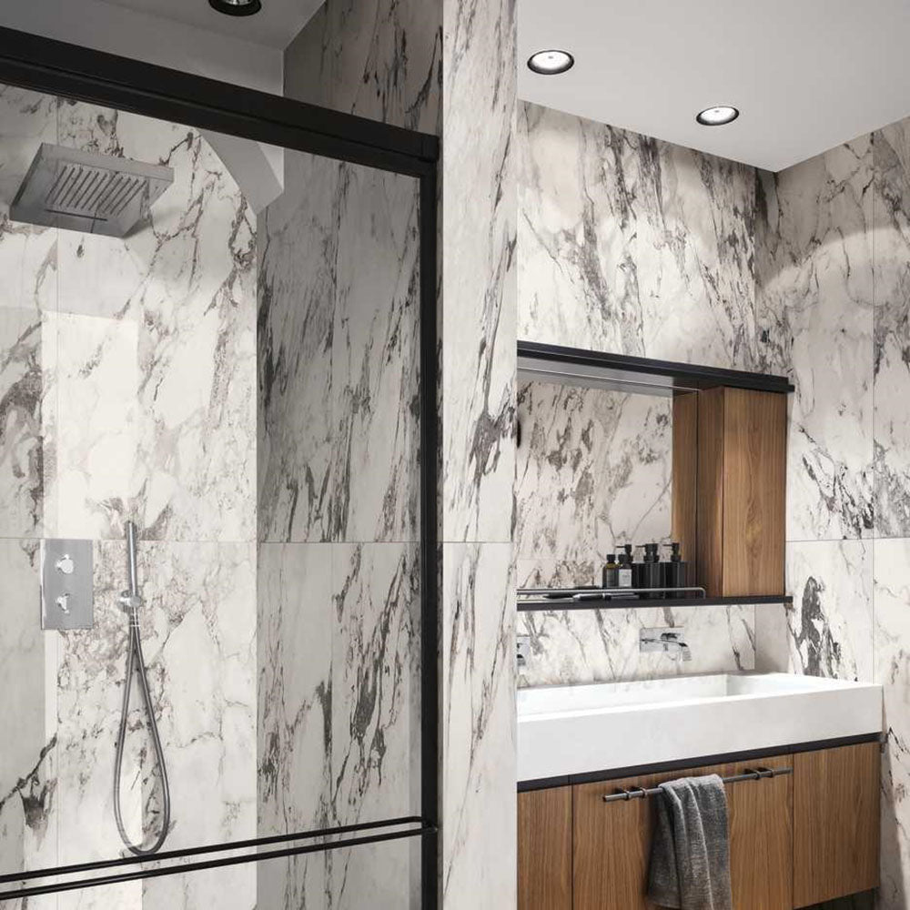 Bathroom interior featuring Hudson Capraia Matt Marble 60 × 120cm porcelain wall tiles, showcasing a crisp white base with bold, dramatic grey veining, paired with black-framed shower detailing and warm wood cabinetry for a striking, contemporary contrast.