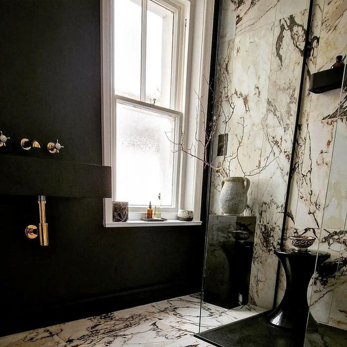Bathroom interior featuring Hudson Capraia Matt Marble 60 × 60cm porcelain wall and floor tiles, styled with bold dark veining against a soft white base, paired with black fixtures and warm brass accents for a striking, contemporary contrast.