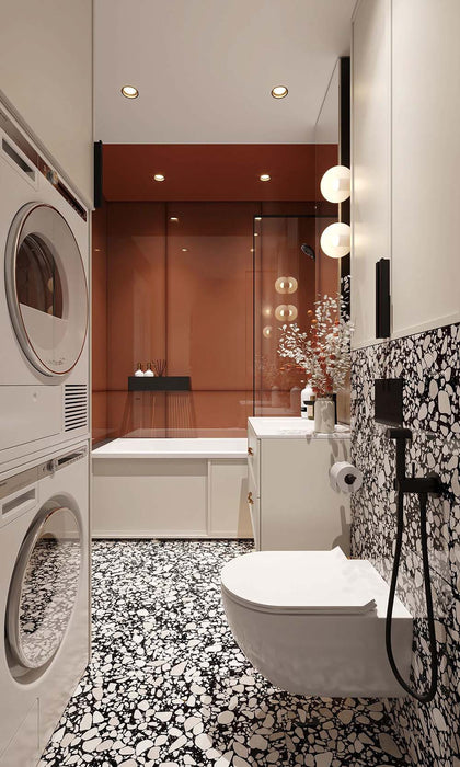 Bathroom setting featuring Shards Terrazzo Nero 59x59cm matt porcelain wall and floor tiles, showcasing a bold terrazzo effect with large white stone fragments set against a deep black base, used across both floor and feature wall, paired with crisp white sanitaryware, warm terracotta tones and soft lighting for a balanced, contemporary contrast.