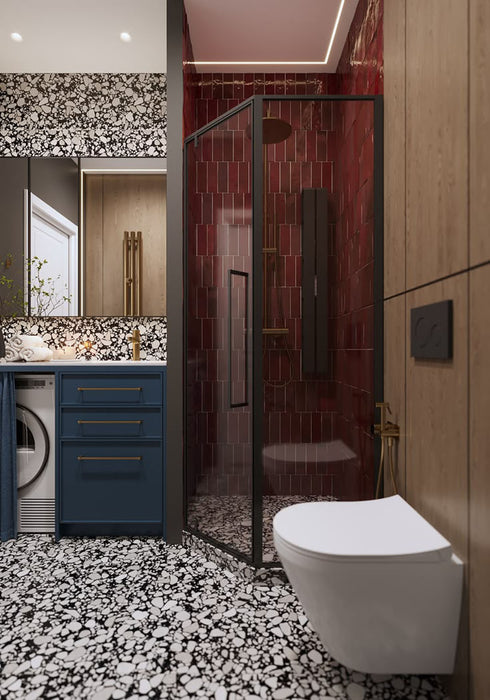 Bathroom setting featuring Shards Terrazzo Nero 59x118cm matt porcelain wall and floor tiles, showcasing a bold black base with contrasting white aggregate, paired with deep red brick tiles, blue cabinetry and brass fittings for a striking, contemporary finish.