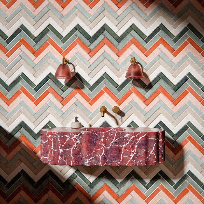 Bathroom interior featuring Puzzle Collection gloss brick tiles, installed in a bold herringbone pattern across walls and floor, blending warm terracotta, soft blush, sage green and cream tones for a statement finish.