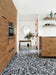 Kitchen setting featuring Shards Terrazzo Nero 59x118cm matt porcelain wall and floor tiles, showcasing a bold black base with contrasting white aggregate, paired with warm wood cabinetry, open shelving and a clean, contemporary finish.