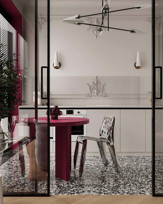 Dining space featuring Shards Terrazzo Nero 59x59cm matt porcelain floor tiles, showcasing a bold terrazzo effect with large white stone fragments set against a deep black base, used across the floor to anchor the space, paired with sculptural furniture, soft neutral cabinetry and striking red accents for a refined, contemporary contrast.