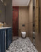 Bathroom setting featuring Shards Terrazzo Nero 59x118cm matt porcelain wall and floor tiles, showcasing a bold black base with contrasting white aggregate, paired with deep red brick tiles, blue cabinetry and brass fittings for a striking, contemporary finish.