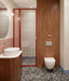 Bathroom setting featuring Shards Terrazzo Nero 59x59cm matt porcelain floor tiles, showcasing a bold terrazzo effect with large white stone fragments set against a deep black base, used across the floor to ground the space, paired with soft pink wall tiles, warm wood finishes and red accents for a playful yet design-led contrast.