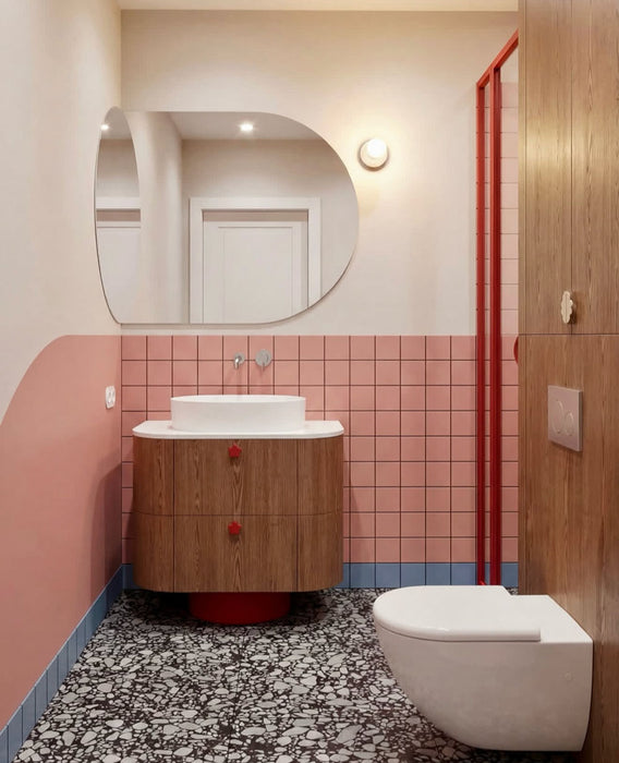 Bathroom setting featuring Shards Terrazzo Nero 59x59cm matt porcelain floor tiles, showcasing a bold terrazzo effect with large white stone fragments set against a deep black base, used across the floor to ground the space, paired with soft pink wall tiles, warm wood finishes and red accents for a playful yet design-led contrast.