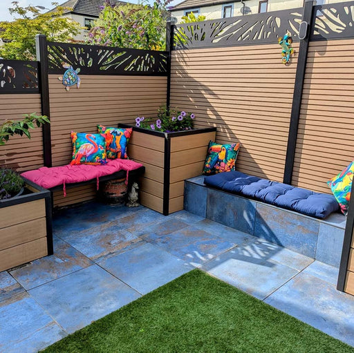 Outdoor patio featuring Iron Blue Oxide Metallic 60 × 60cm porcelain floor tiles, styled with deep blue tones and warm oxidised variation, creating a textured, industrial-inspired surface, paired with timber seating, vibrant cushions, and greenery for a bold yet inviting garden setting.