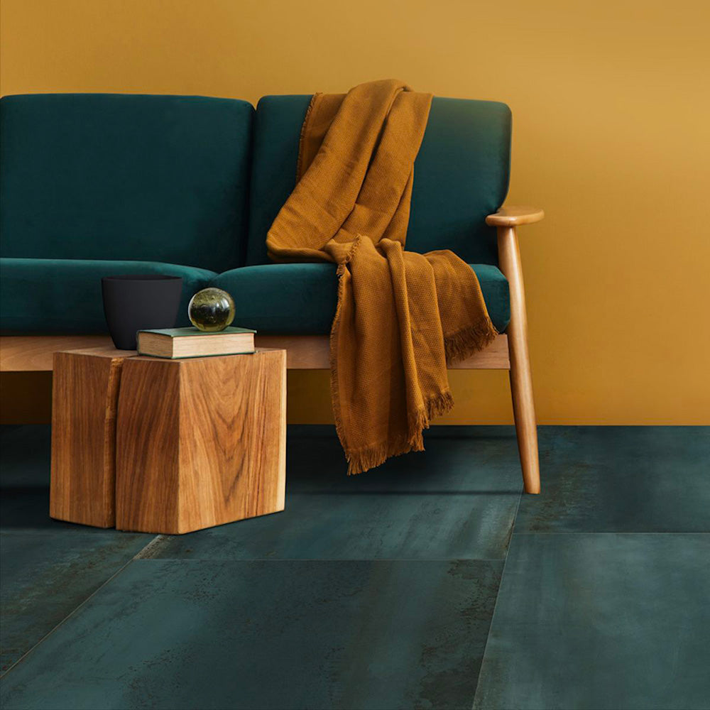 Living room setting featuring Iron Cuprum Oxide Metallic 60 × 60cm porcelain floor tiles, showcasing rich copper-toned hues with subtle tonal variation and a softly textured metallic effect, paired with warm wood furniture and deep upholstery for a bold, contemporary finish.