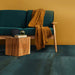 Living room setting featuring Iron Cuprum Oxide Metallic 60 × 60cm porcelain floor tiles, showcasing rich copper-toned hues with subtle tonal variation and a softly textured metallic effect, paired with warm wood furniture and deep upholstery for a bold, contemporary finish.
