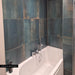 Bathroom interior featuring Iron Cuprum Oxide Metallic 60 × 60cm porcelain wall tiles, showcasing deep blue-green tones with warm coppery oxidation and soft tonal variation, paired with a white bath and chrome fittings for a striking, industrial-inspired finish.