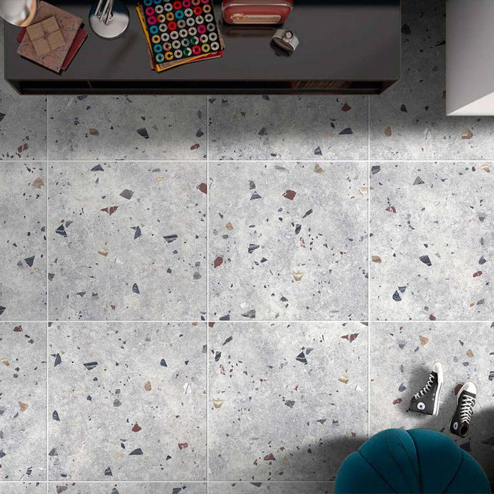Top-down interior view featuring Jericho Silver Terrazzo 66 × 66cm porcelain wall and floor tiles, showcasing a soft grey base scattered with multicoloured aggregate chips, styled with modern furnishings for a clean, contemporary finish.