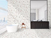 Bathroom interior featuring Jericho White Terrazzo Hexagon 25 × 22cm porcelain wall and floor tiles, with a crisp white base and multicoloured aggregate chips, laid in a continuous honeycomb pattern and paired with a freestanding bath and dark wood vanity for a clean, contemporary contrast.