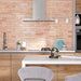Kitchen splashback featuring Allegra Tusk Pink Gloss Brick ceramic tiles in a 6 × 25cm format, creating a warm, contemporary look with a soft pink gloss finish paired with light wood cabinetry and modern fittings.