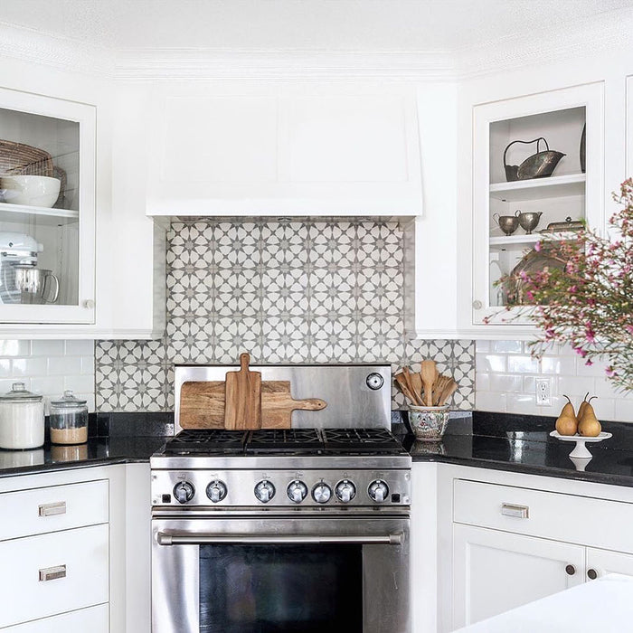 Agadir Silver Moroccan-style 20x20cm porcelain tiles used as a kitchen splashback, showcasing a subtle grey and white geometric pattern behind a stainless steel range cooker in a bright white kitchen.