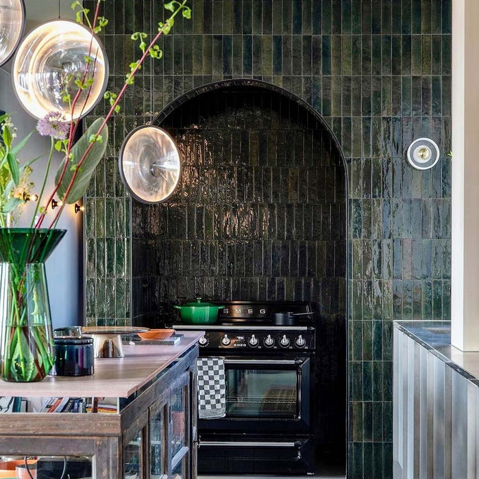 Kitchen setting featuring Levent Green 6x24cm porcelain wall and floor tiles, showcasing rich tonal variation and a glossy finish, installed in a striking arched alcove to frame the cooking area and create a bold, characterful focal point.