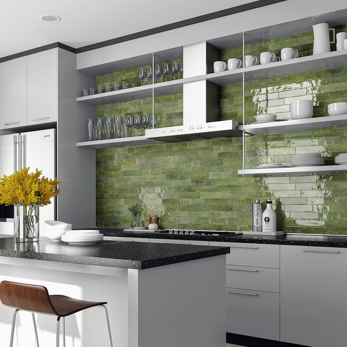 Modern kitchen featuring Nomad Sage Green brick wall tiles in a 6 × 24.6cm format, with a glossy textured finish that adds depth and an industrial-style look behind open shelving and worktops.