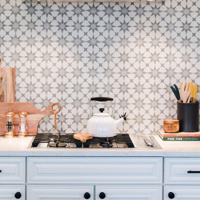 Agadir Silver Moroccan-style 20x20cm porcelain tiles used as a kitchen splashback, featuring a soft grey and white geometric star pattern behind a white cooker with wooden accessories.