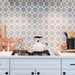 Agadir Silver Moroccan-style 20x20cm porcelain tiles used as a kitchen splashback, featuring a soft grey and white geometric star pattern behind a white cooker with wooden accessories.