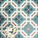 Group of London Streets Leicester Square 20x20cm Victorian Moroccan style porcelain tiles arranged to display the repeating teal, cream and terracotta geometric pattern, styled with white flowers in a decorative flat-lay setting.