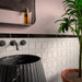 Bathroom featuring Levent Antique White Brick gloss porcelain wall tiles in 6cm x 24cm, showcasing soft antique white tones with a glossy finish, paired with a black marble border tile, blush pink walls, a fluted black marble pedestal basin, matt black brassware and a contemporary interior.