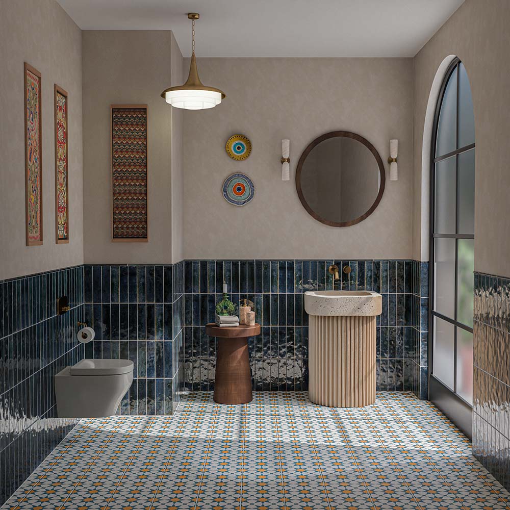 Contemporary bathroom featuring Levent Blue 6x24cm glossy brick wall tiles, with deep navy blue tones and textured glaze variation, paired with colourful Moroccan-style patterned floor tiles, a fluted cream basin, brass fittings and neutral walls.
