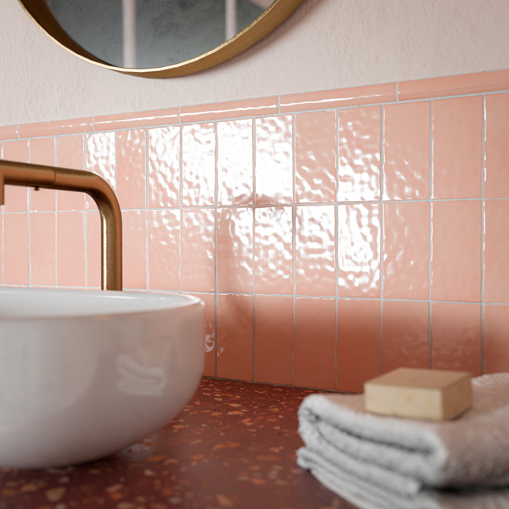 Liberty Blush Pink 7.5cm x 15cm rustic effect gloss wall tiles, featuring a softly rippled surface and blush pink finish in a vertical layout, paired with a terrazzo effect worktop and warm brass details.