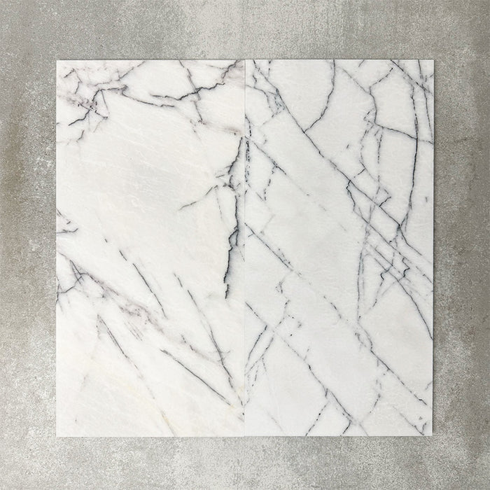 Close-up of Fayrouz Lilac natural marble tiles in a honed finish, 30.5x61cm format, showcasing a soft white base with delicate lilac and grey veining, creating a subtle yet refined look for wall and floor applications.