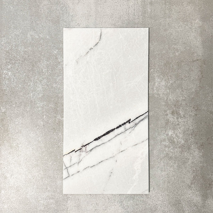 Fayrouz Lilac 30.5x61cm natural marble tiles with a honed finish, featuring a soft white base with subtle lilac undertones and fine grey veining, shown as a single tile sample against a neutral textured backdrop.