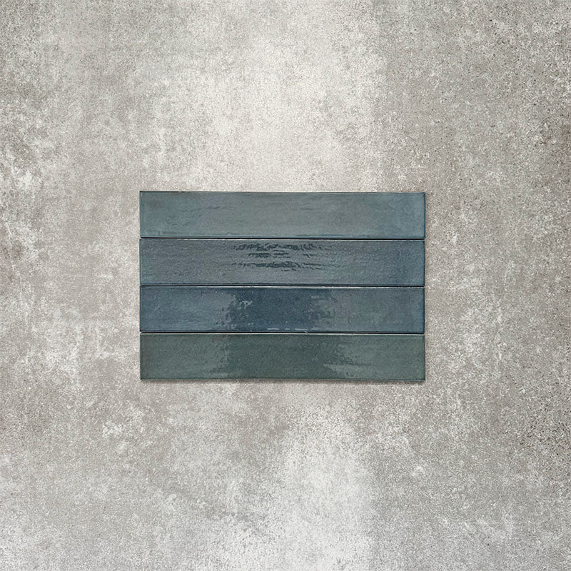 Close-up of Lisbon Blue 5cm x 30cm artisanal porcelain wall tiles arranged horizontally, showcasing rich blue-grey tones, subtle tonal variation and a handcrafted-effect surface finish.