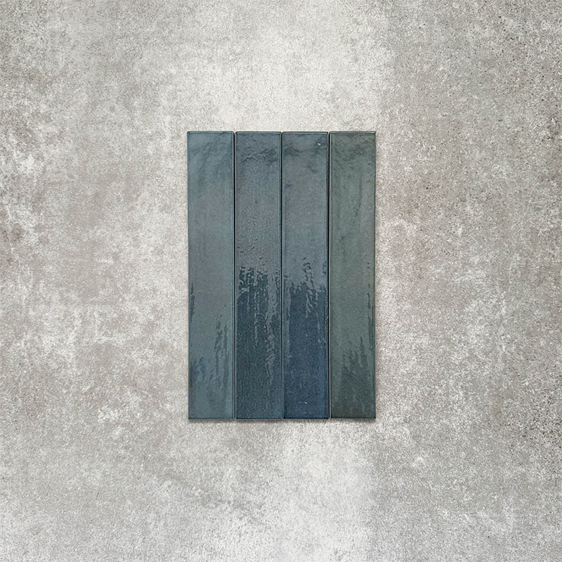 Close-up of Lisbon Blue 5cm x 30cm artisanal porcelain wall tiles arranged vertically, showcasing rich blue-grey tones, subtle tonal variation and a handcrafted-effect surface finish.