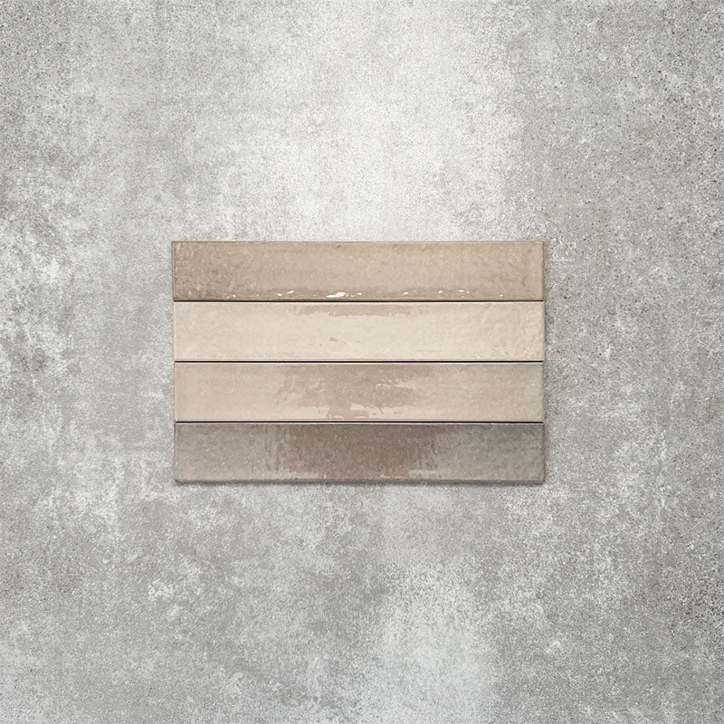 Close-up of Lisbon Grey 5cm x 30cm artisanal porcelain wall tiles arranged horizontally, showcasing warm grey and taupe tones, subtle tonal variation and a handcrafted-effect surface finish.