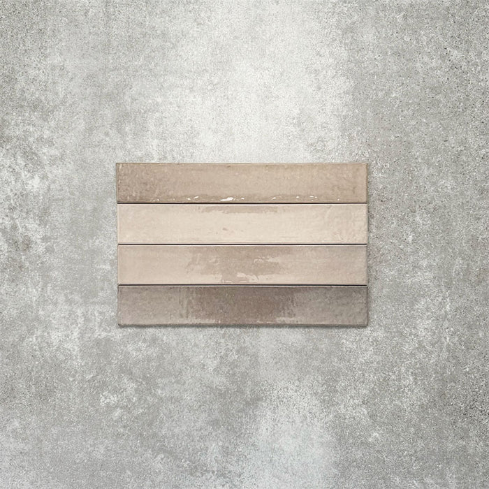 Close-up of Lisbon Grey 5cm x 30cm artisanal porcelain wall tiles arranged horizontally, showcasing warm grey and taupe tones, subtle tonal variation and a handcrafted-effect surface finish.