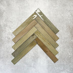 Close-up of Lisbon Olive Green 5cm x 30cm artisanal porcelain wall tiles arranged in a herringbone pattern, showcasing earthy olive green tones, tonal variation and a glossy handcrafted-effect surface finish.