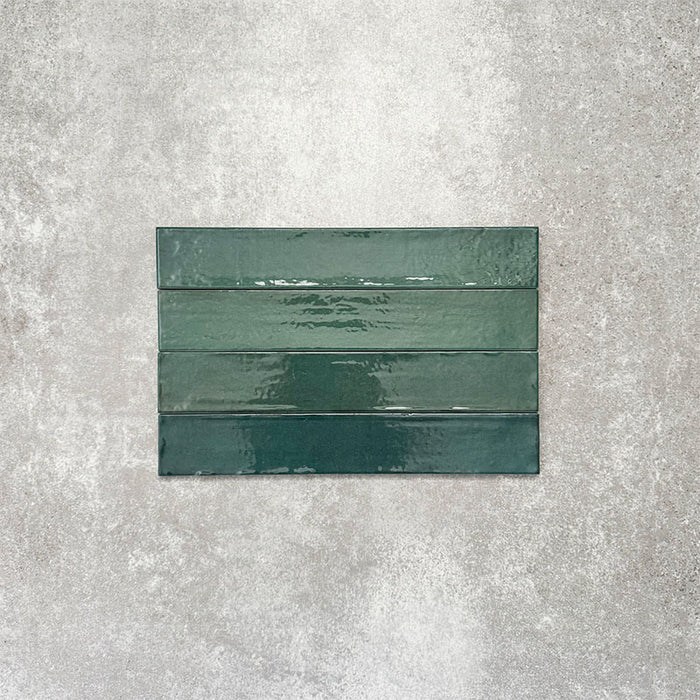 Close-up of Lisbon Verde Green 5cm x 30cm artisanal porcelain wall tiles arranged horizontally, showcasing rich green tones, subtle tonal variation and a glossy handcrafted-effect surface finish.
