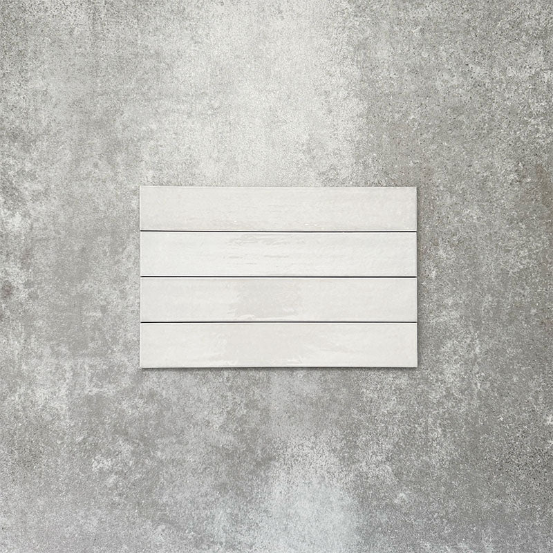 Close-up of Lisbon White 5cm x 30cm artisanal porcelain wall tiles arranged horizontally, showcasing soft white tones, subtle tonal variation and a handcrafted-effect surface finish.
