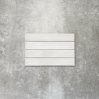 Close-up of Lisbon White 5cm x 30cm artisanal porcelain wall tiles arranged horizontally, showcasing soft white tones, subtle tonal variation and a handcrafted-effect surface finish.