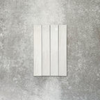 Close-up of Lisbon White 5cm x 30cm artisanal porcelain wall tiles arranged vertically, showcasing soft white tones, subtle tonal variation and a handcrafted-effect surface finish.