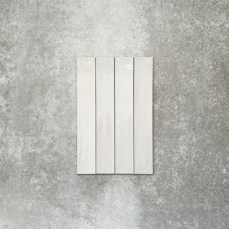 Close-up of Lisbon White 5cm x 30cm artisanal porcelain wall tiles arranged vertically, showcasing soft white tones, subtle tonal variation and a handcrafted-effect surface finish.