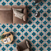 Living room interior featuring London Streets Leicester Square 20x20cm Victorian Moroccan style floor tiles, styled with a neutral sofa, armchair, round coffee table and modern floor lamp, showcasing a bold teal and cream patterned floor.