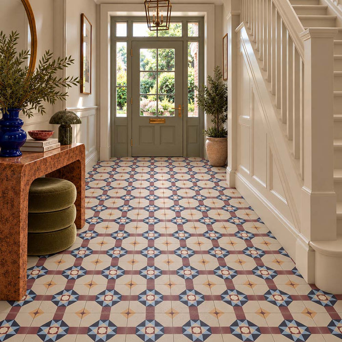 Elegant hallway featuring London Streets Berlin Street 20x20cm Victorian and Moroccan style patterned floor tiles, with blue, burgundy and ochre geometric motifs, complemented by cream panelling, a wooden console table and a sage green front door.