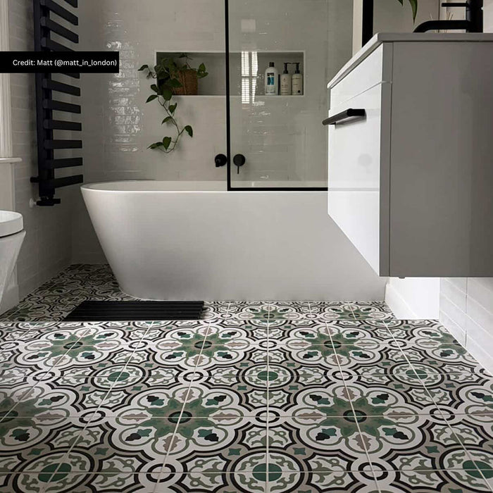 Bathroom interior featuring London Streets Bond Street 20 × 20cm Victorian Moroccan-style porcelain floor tiles, styled with an intricate green, grey, and black patterned design, paired with glossy white wall tiles, matte black fittings, and a freestanding bath for a bold, timeless look.